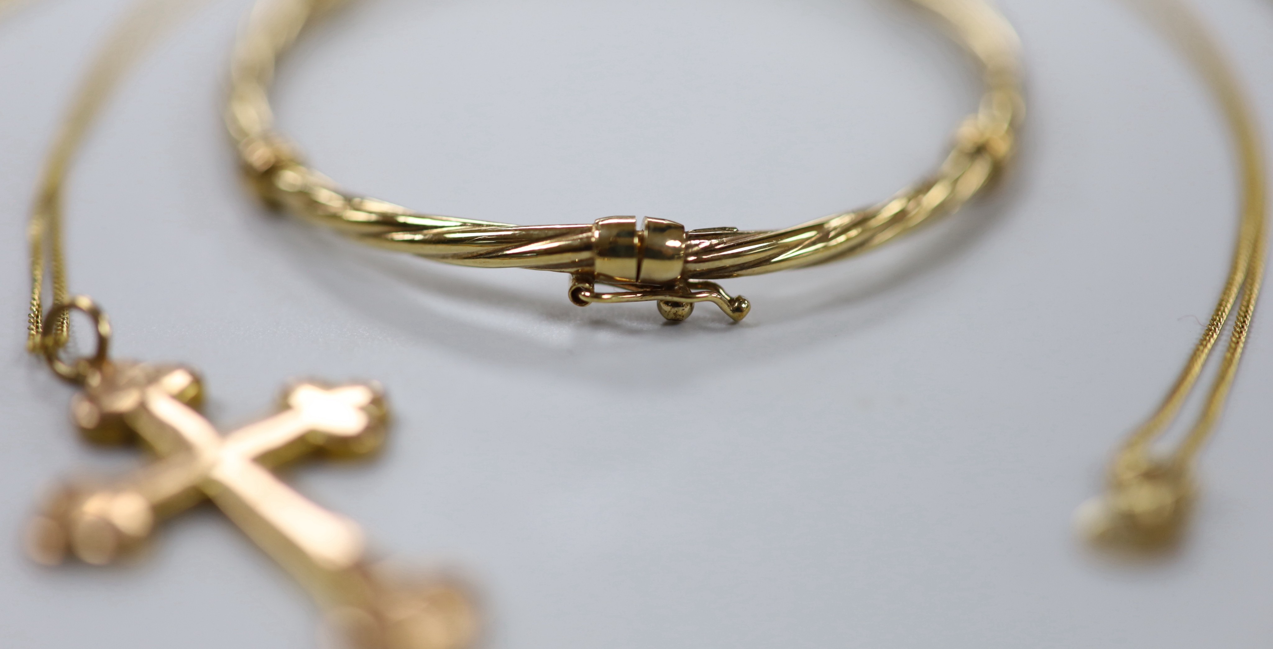 Two 9ct pendant necklaces, one with cross pendant, a 9ct gold hinged bangle and a 9ct chain, 23.4 grams.